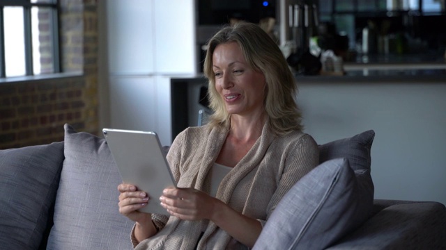 漂亮的白人女人在家里用平板电脑视频通话，一边说话一边微笑视频素材
