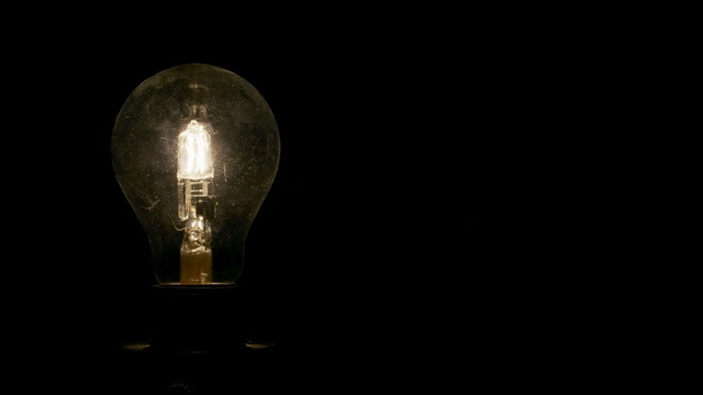 一个昏暗的，暖色的，球形灯泡在黑色的背景视频下载