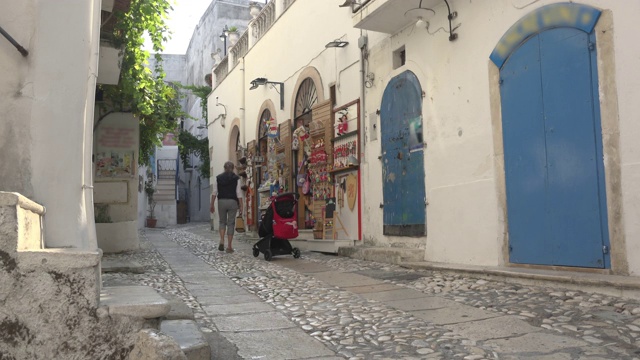 一名妇女走在Peschici老城的商店巷子里视频素材