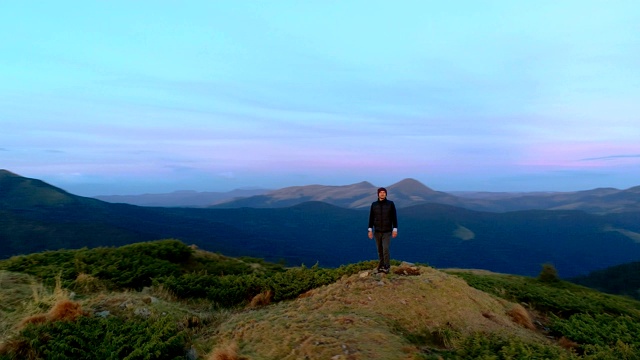 在美丽的落日余晖中，一个人站在山顶视频素材