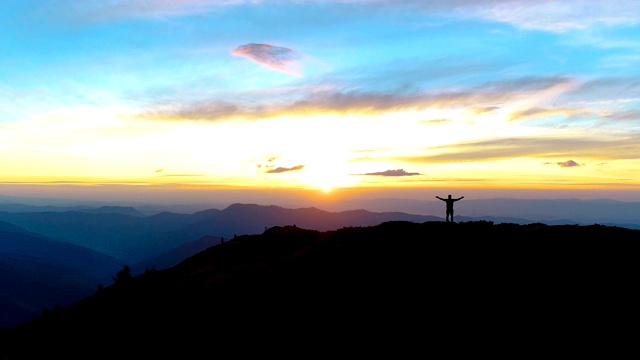 快乐的雄站在山的夕阳背景上视频素材