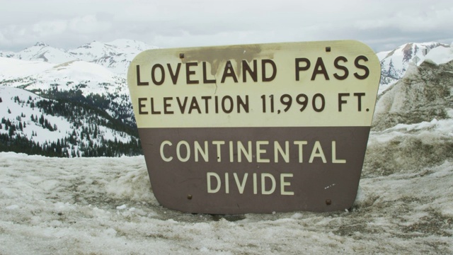 “Loveland Pass: Elevation 11,990 Ft. Continental Divide”标志，位于Loveland Pass的顶部，背景是科罗拉多州的落基山脉，在冬季的阴天下视频下载