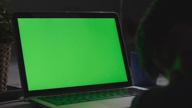肩上的照片是一个小男孩在桌上使用笔记本电脑，看着绿色的屏幕。多莉60 fps射击。视频素材