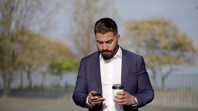 拿着咖啡要走的男人在户外用手机视频素材