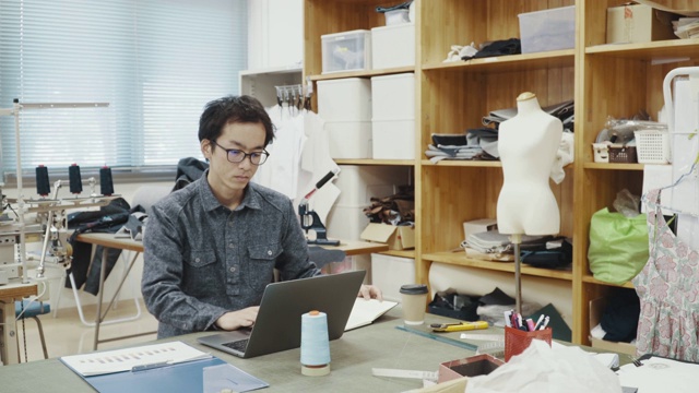 中等拍摄的中年设计专业人员在一个纺织厂的电脑工作视频素材