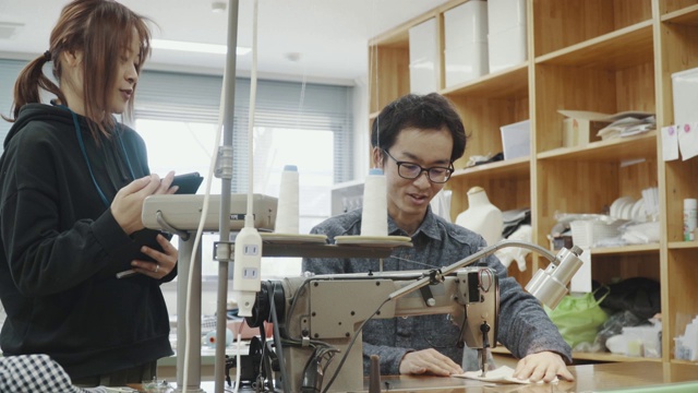 中镜头的两个中年设计专业人员一起工作在纺织制造工作室视频素材