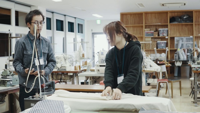 中镜头的两个中年设计专业人员一起工作在纺织制造工作室视频素材