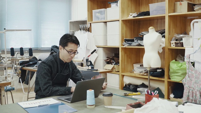 中等拍摄的中年设计专业人员在一个纺织厂的电脑工作视频素材