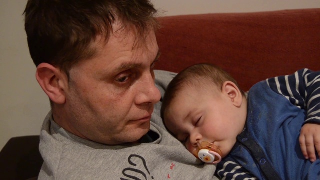 疲惫的父亲让他六个月大的儿子睡着了视频下载
