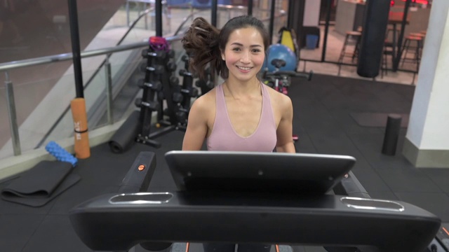 在健身俱乐部跑步机上跑步的亚裔中国女运动员视频素材