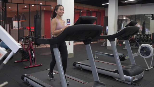 在健身俱乐部跑步机上跑步的亚裔中国女运动员视频素材