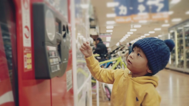 亚洲小男孩正在往自动贩卖机里捡水瓶。视频下载