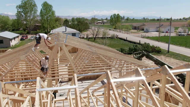 无人机拍摄的两名白人男性建筑工人在一个阳光明媚的日子里搭建房屋视频素材
