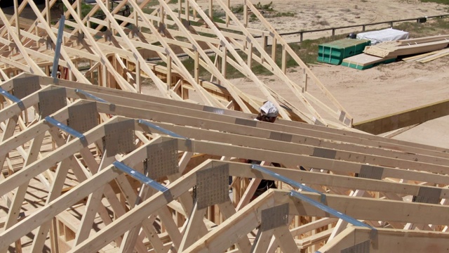 无人机拍摄的一名40多岁的白人男性建筑工人在一个阳光明媚的日子里搭建房子视频素材