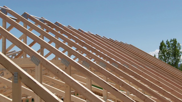 无人机拍摄的一排木屋顶桁架在一个阳光明媚的日子在一个建筑工地视频素材