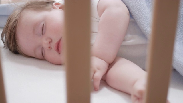 一个美丽的婴儿安静地睡在他的婴儿床的特写视频素材