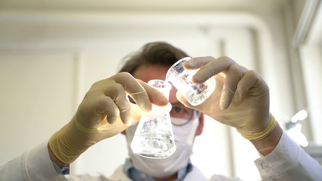 男科学家在实验室里搅拌烧瓶里的液体视频下载