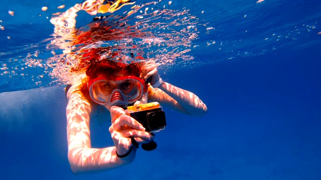 浮潜女孩与一个行动相机浮在海上，并拍摄一个摄像机视频下载