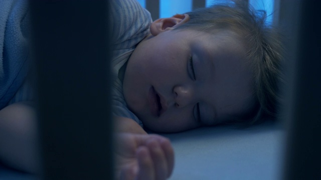 夜间拍摄——可爱的婴儿安静地睡在他的婴儿床里视频素材