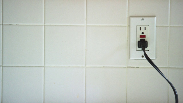 一名白人妇女的手插入一根电线到一个垂直的美国电源插座，然后拔下电线视频下载