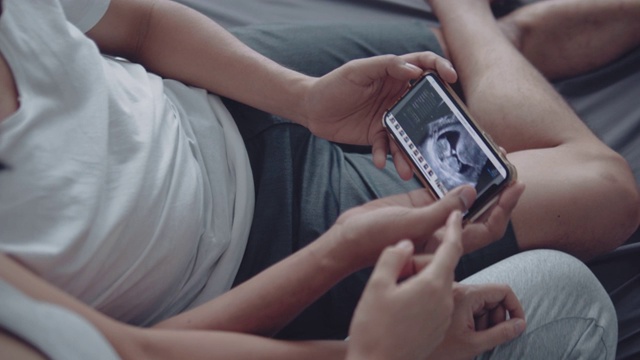 一对怀孕夫妇在智能手机上看超声波视频视频下载