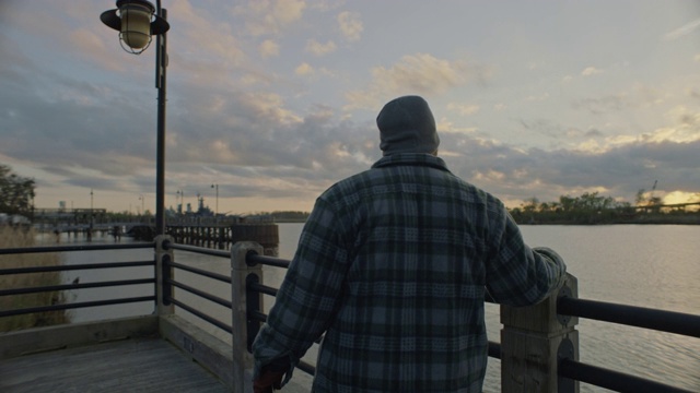 一个人走在风景优美的河边步道上，看着夕阳下的开普菲尔河。视频素材