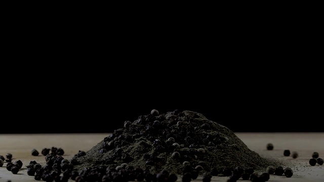黑胡椒花椒落在黑胡椒堆上的慢动作镜头，背景是黑色。视频素材