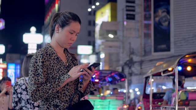 女性在晚上用智能手机请求和等待出租车。视频素材