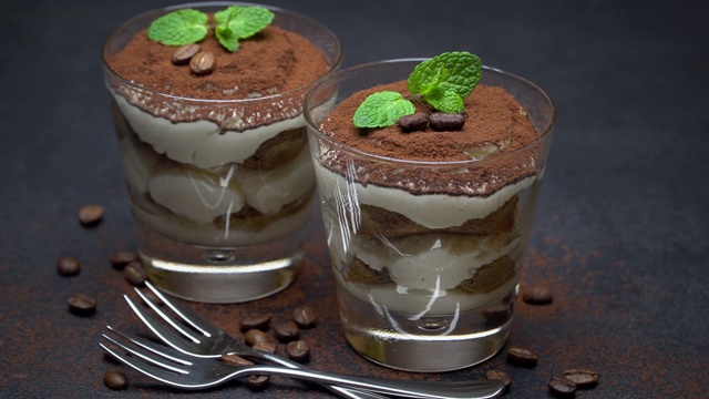 两份经典的提拉米苏甜点放在一个玻璃杯里，背景是深色的混凝土视频素材