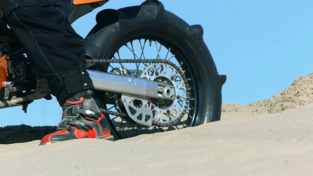 摩托车轮胎在沙子中旋转的特写，慢镜头视频素材