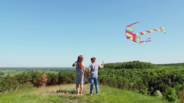男孩和女孩站在山顶上放风筝视频素材