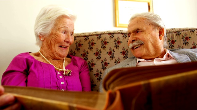 正面的观点积极的白人老年夫妇看相册在疗养院4k视频下载