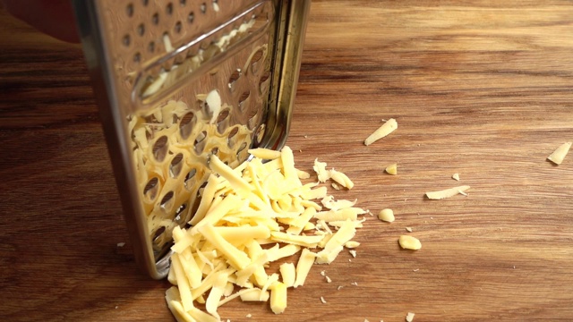 厨师在刨丝器上擦奶酪。缓慢的运动。视频素材