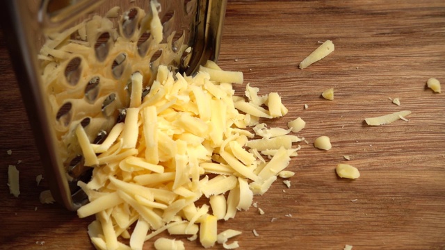 厨师在刨丝器上擦奶酪。缓慢的运动。视频素材
