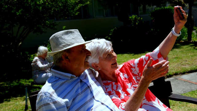 正面视图积极的白人老年夫妇自拍与手机在花园里的护士视频素材