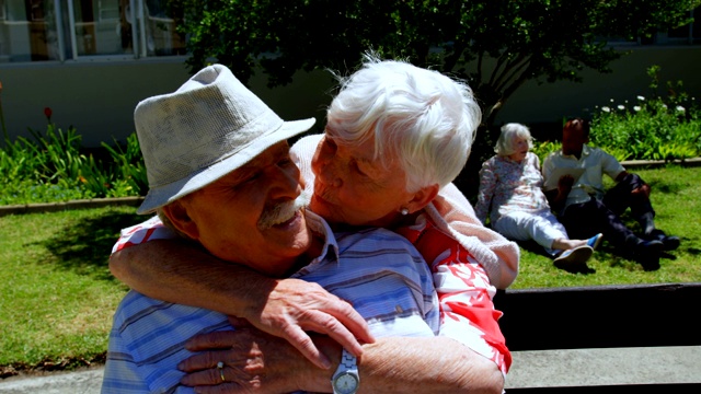 正面的积极白人老年夫妇拥抱对方在花园的养老院4k视频素材
