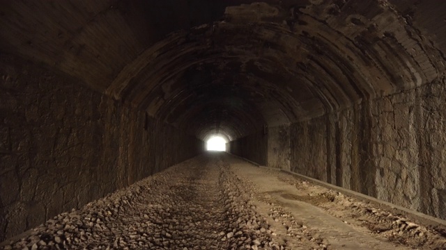 波夫走在古老的黑暗早已废弃的隧道里，带着明亮的灯光走到尽头。视频素材