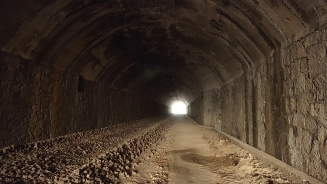 波夫走在古老的黑暗早已废弃的隧道里，带着明亮的灯光走到尽头。视频素材