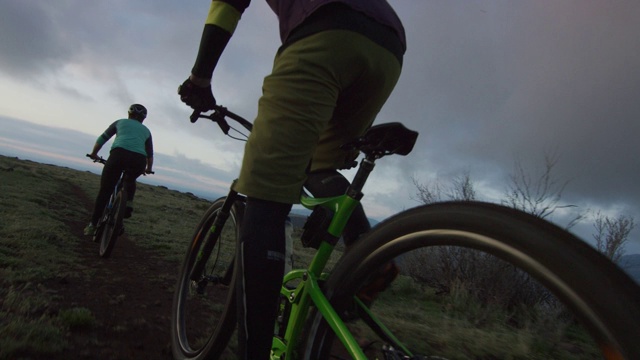 两名骑手(一名女性和一名男性)山地自行车在洛基山脉以西的丹佛，科罗拉多州日出视频素材