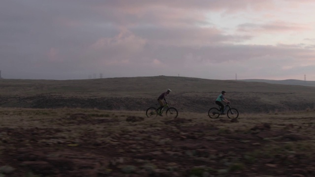 日出时分，在科罗拉多州丹佛市西部的落基山脉，无人机拍摄的两个人(一女一男)骑山地自行车视频素材