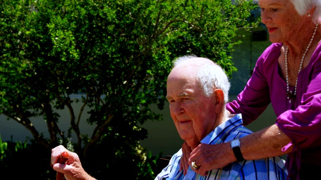 侧面的积极白人老年夫妇拥抱对方在花园的养老院4k视频素材