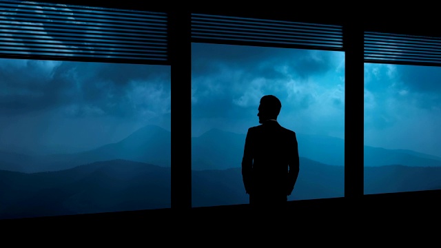 在夜山的背景中，那个男人站在窗前。时间流逝视频下载