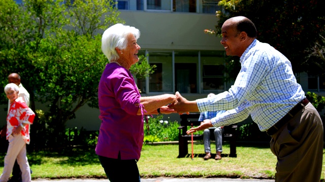 侧视图活跃的混合种族老年夫妇一起跳舞在养老院的花园4k视频下载