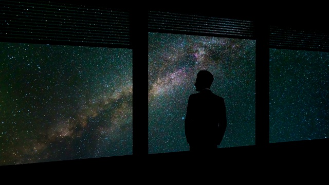 那个商人站在窗前，背景是繁星点点的天空。时间流逝视频下载