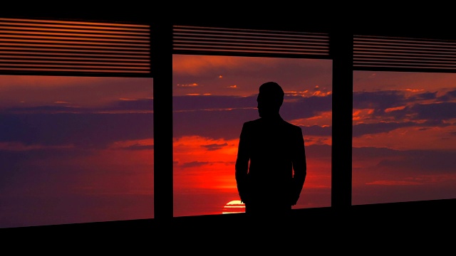 那个男人站在窗前，背景是明亮的阳光。时间流逝视频素材