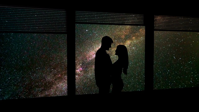 这对情侣站在靠近窗户的流星雨背景下。时间流逝视频素材