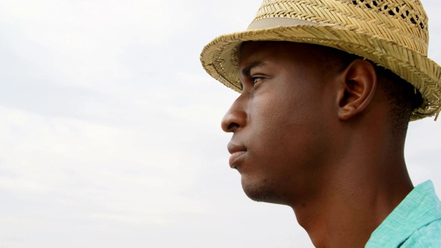 侧面的非洲裔美国人戴着帽子站在海滩上4k视频下载
