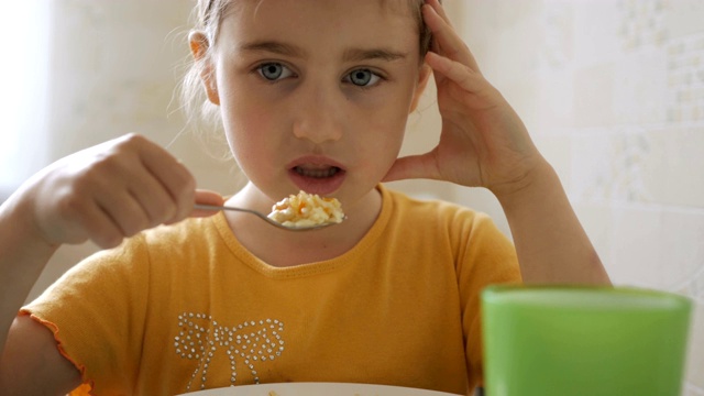 小女孩在家吃早餐。漂亮的美国女孩吃麦片的胃口。孩子在厨房吃早餐。特写镜头。视频素材