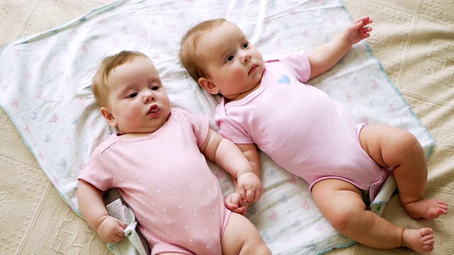 女孩们是穿着粉红色衣服的双胞胎姐妹视频素材