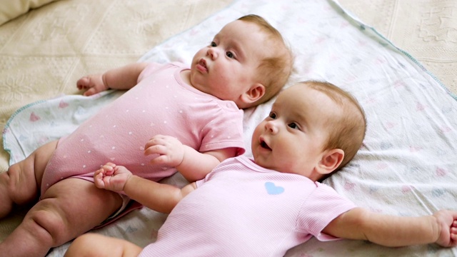 女孩们是穿着粉红色衣服的双胞胎姐妹视频素材